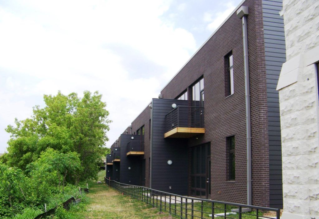 A row of brick buildings with balconies and a fence
