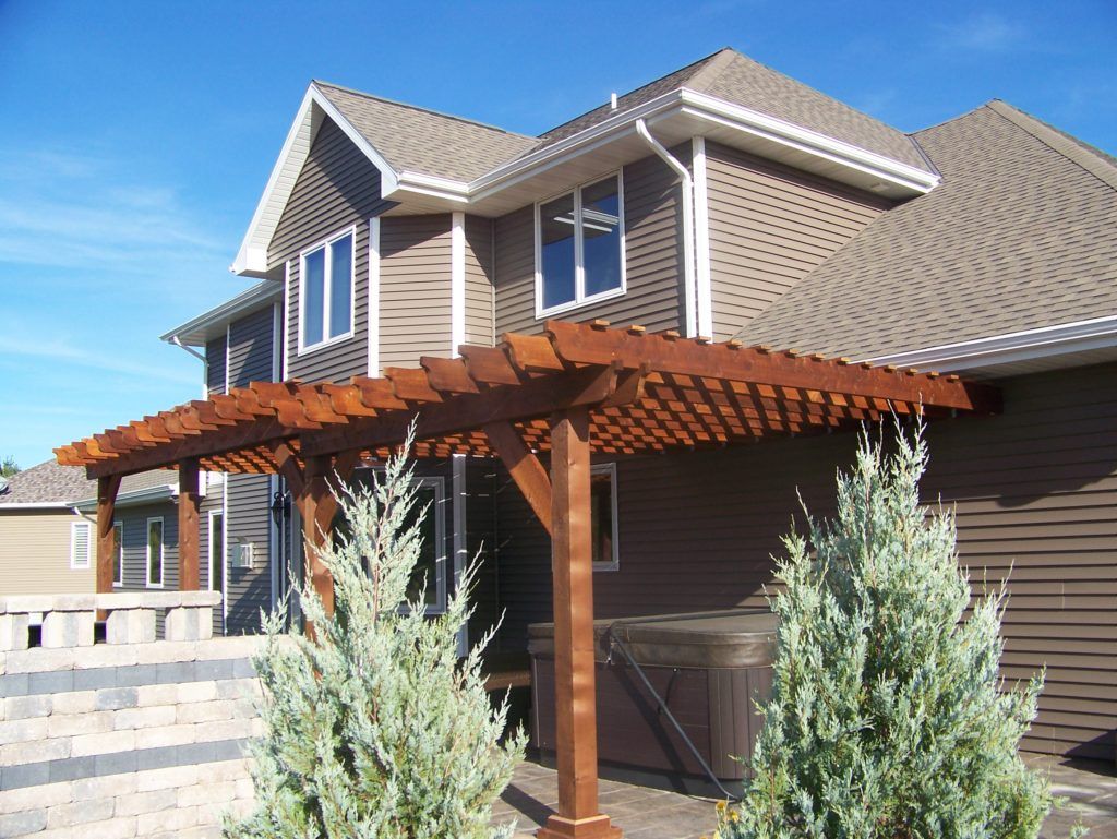 A house with a pergola and a hot tub under it