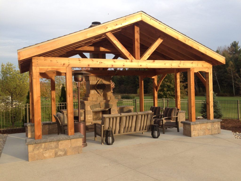 A wooden pavilion with a couch and chairs underneath it