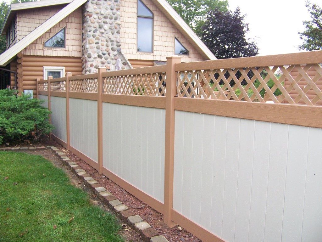 A vinyl fence surrounds a swimming pool with a lattice top