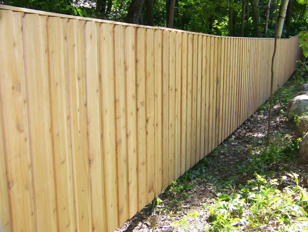 A wooden fence is surrounded by trees and grass