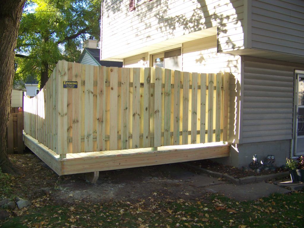 A wooden fence surrounds a deck on a house