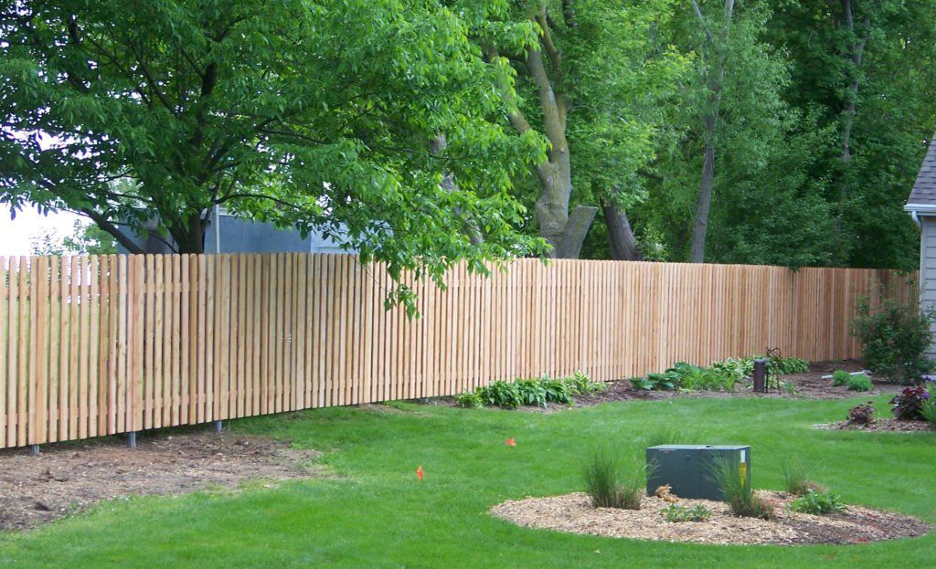 A wooden fence surrounds a lush green yard.