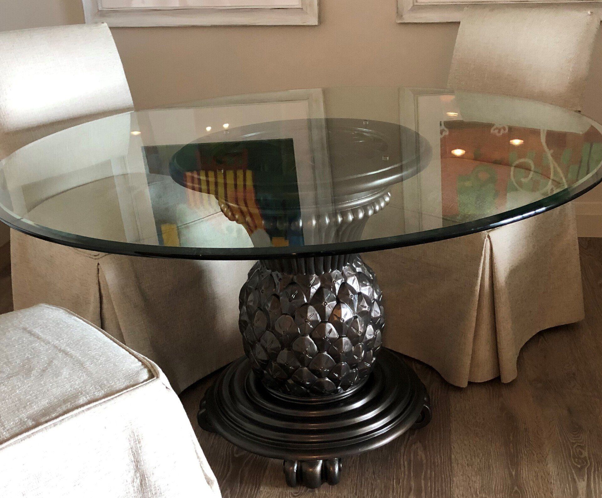 Round glass-top table with a pineapple-shaped base, flanked by two chairs.