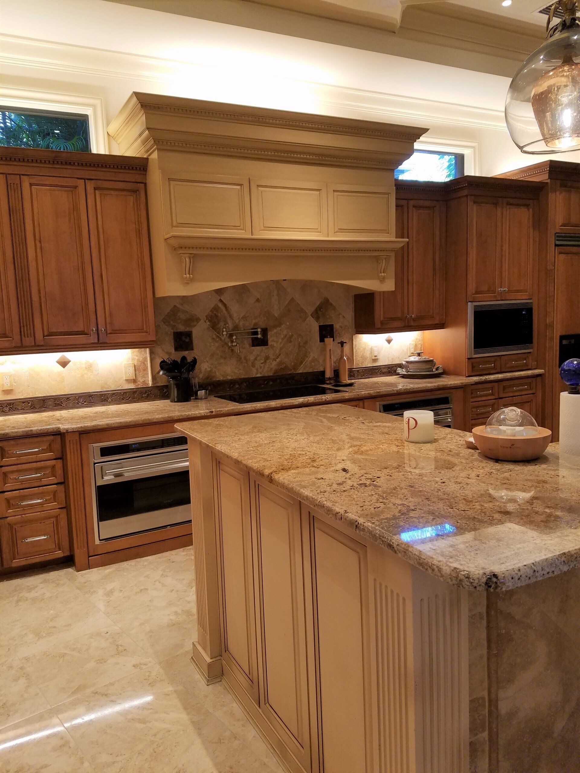 Kitchen with light-colored cabinets and countertop, a large island, and a range hood.