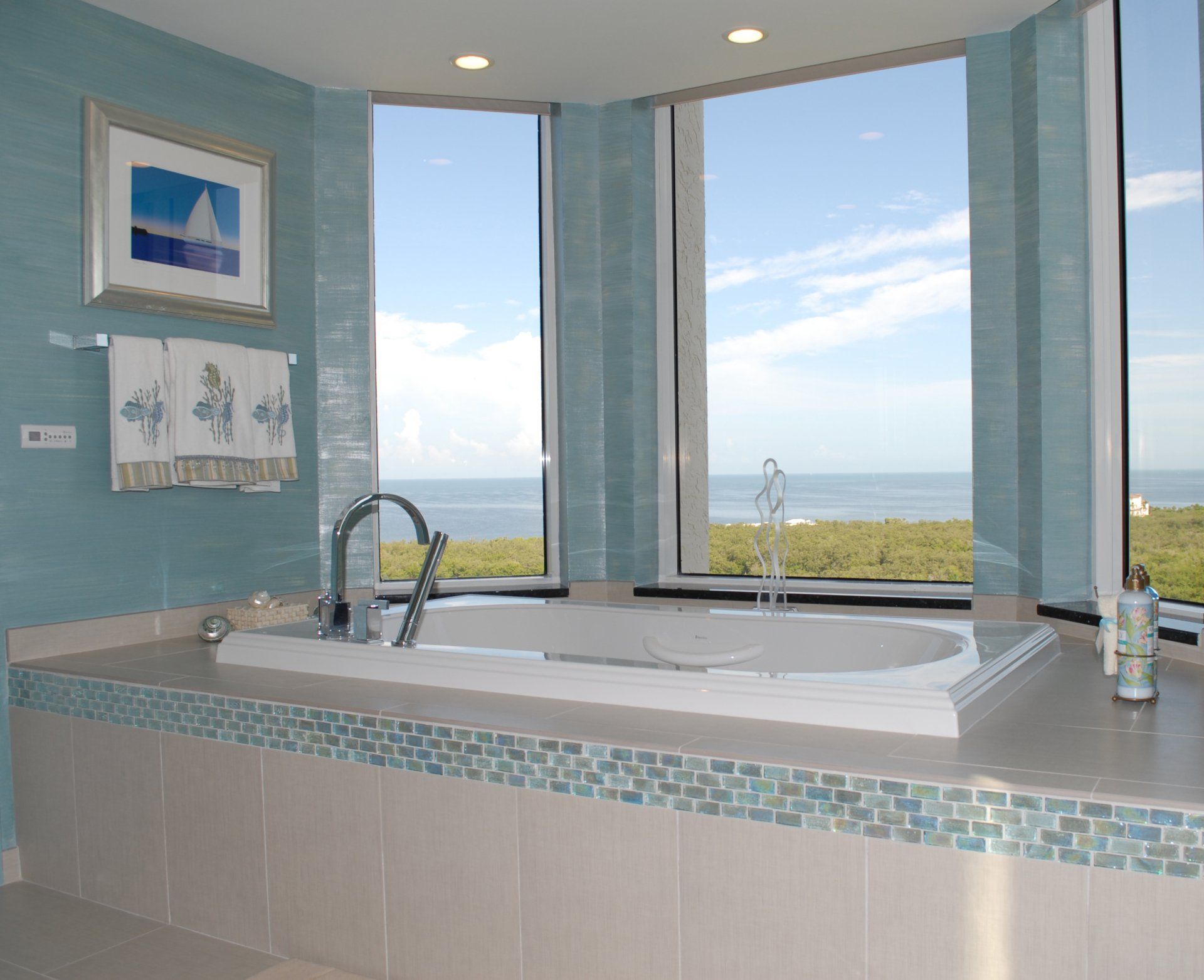 Bathroom with ocean view, blue tile, a jacuzzi tub, and artwork.