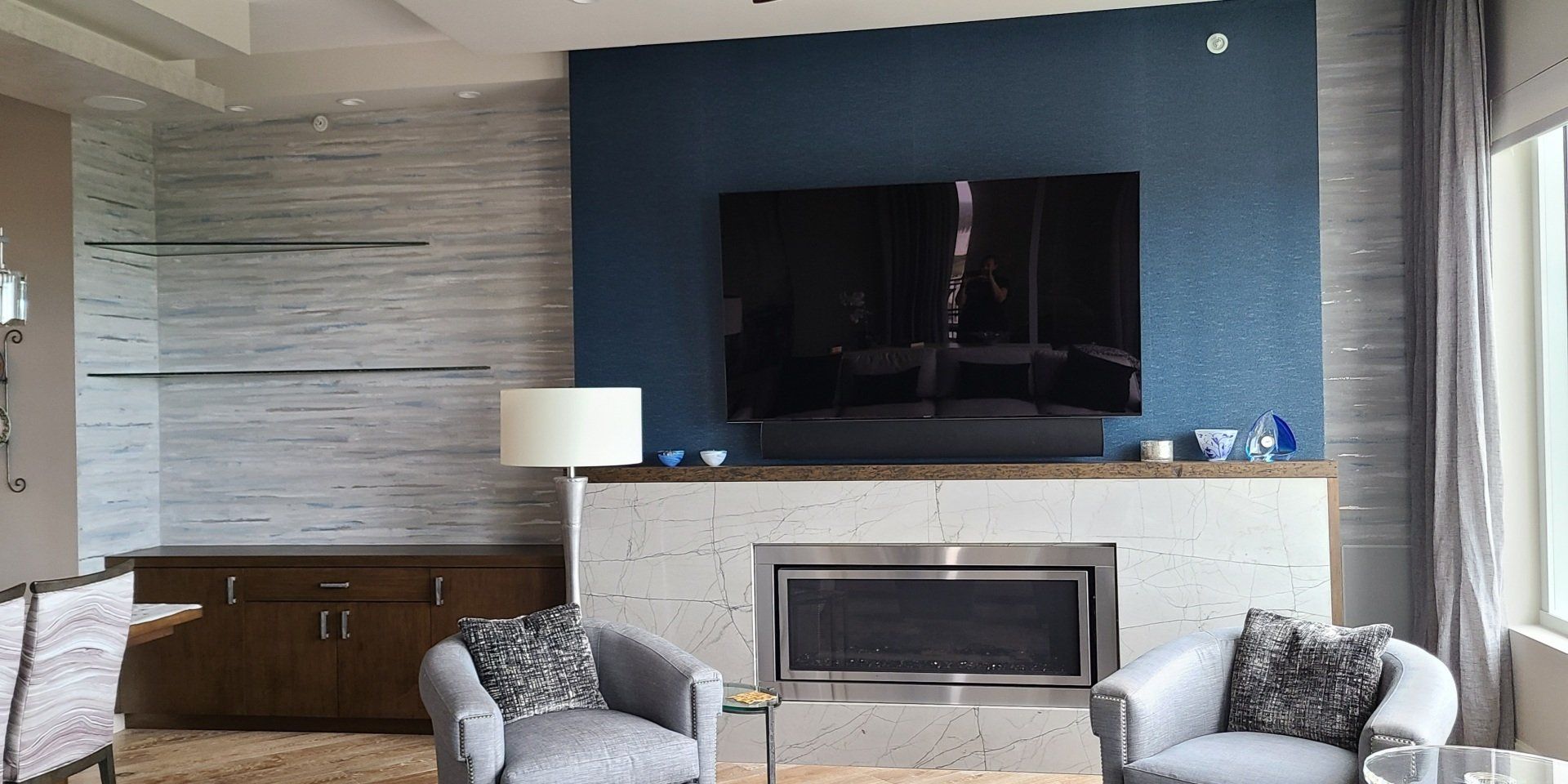 Living room with blue accent wall, fireplace, TV, and two armchairs.