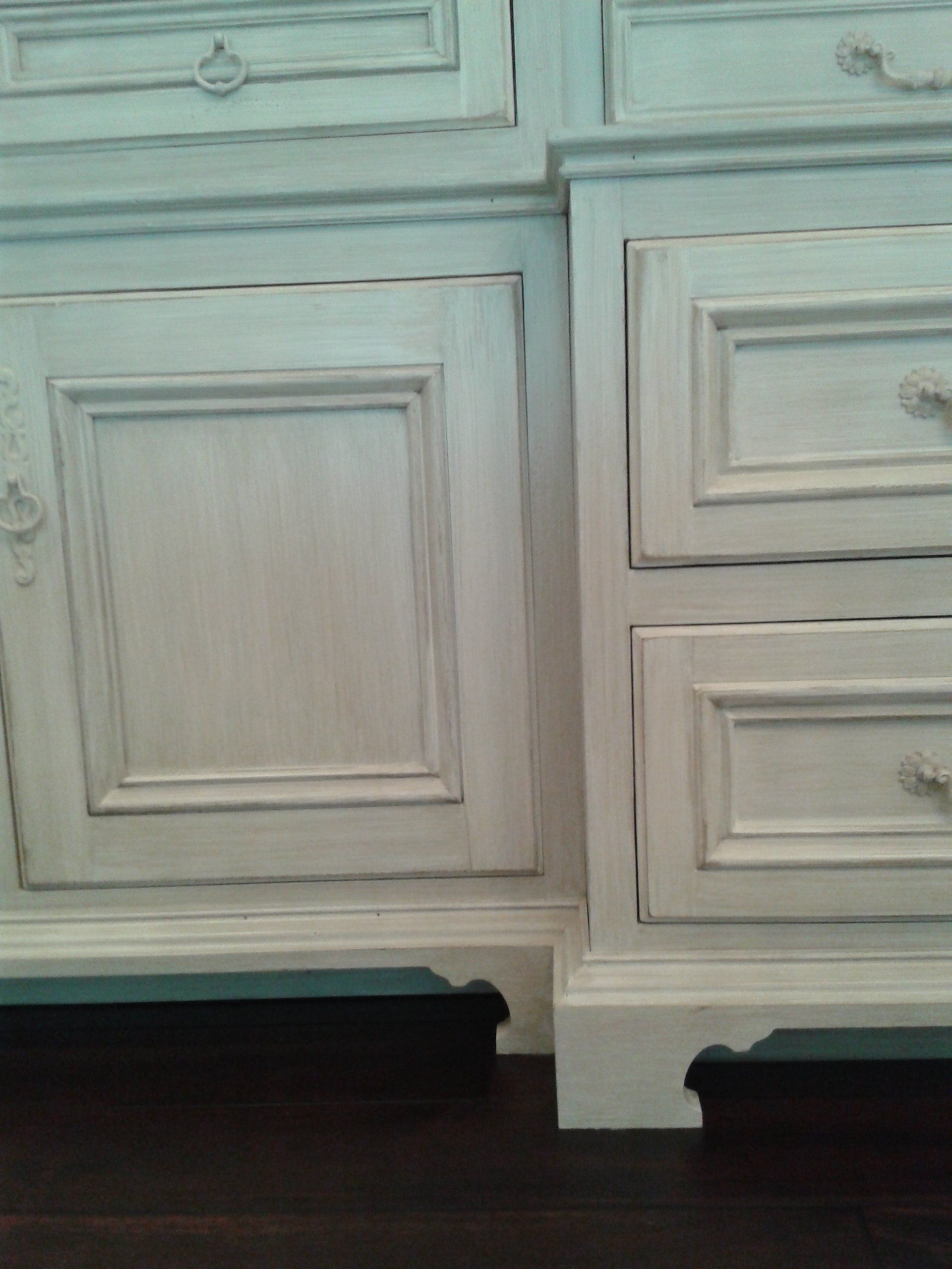 White distressed cabinets, dark trim, dark wood floor.