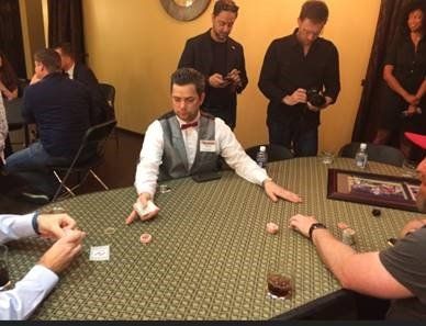 A man in a vest and bow tie is sitting at a table playing poker.
