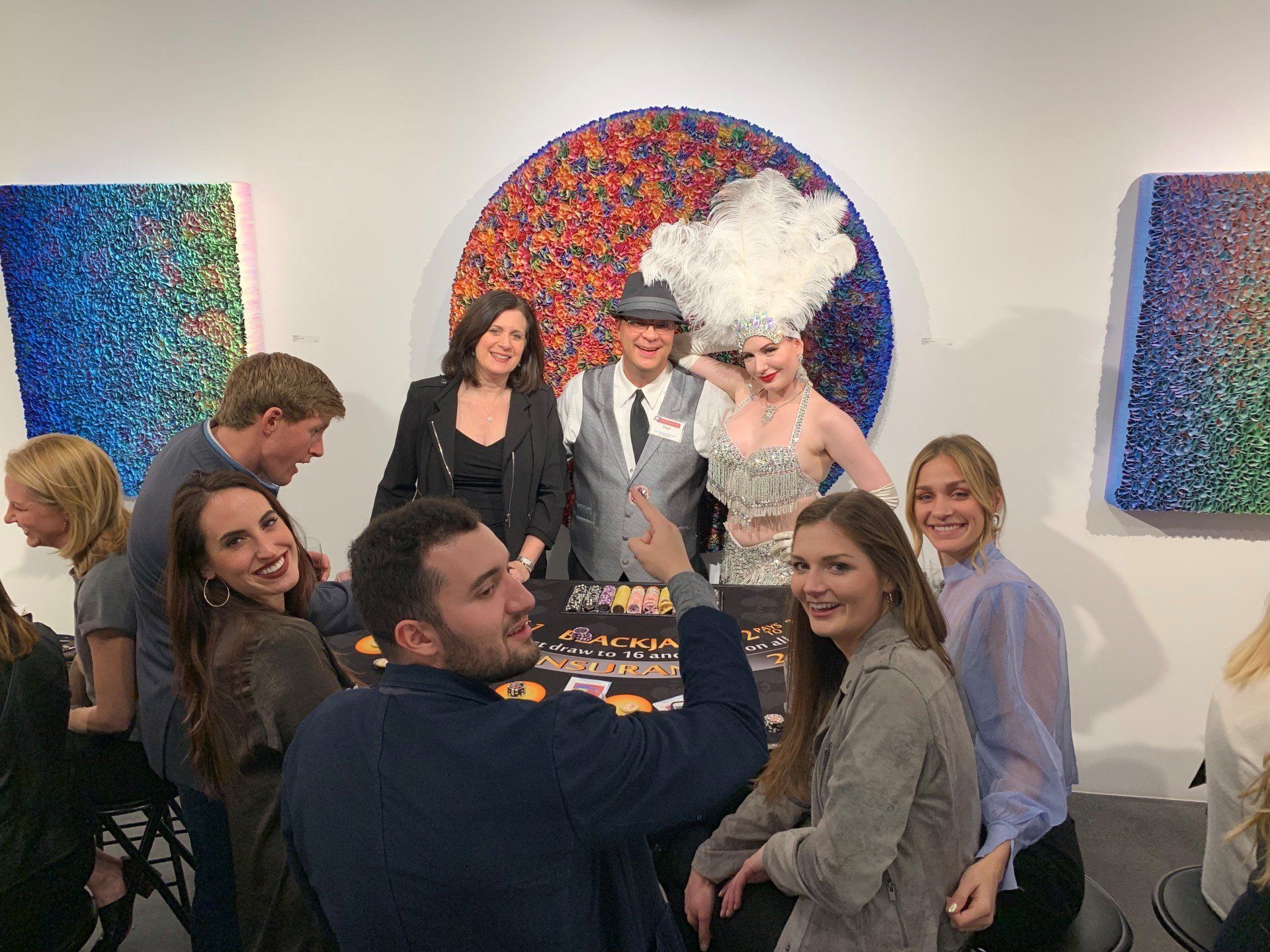 A group of people are posing for a picture in front of a painting.