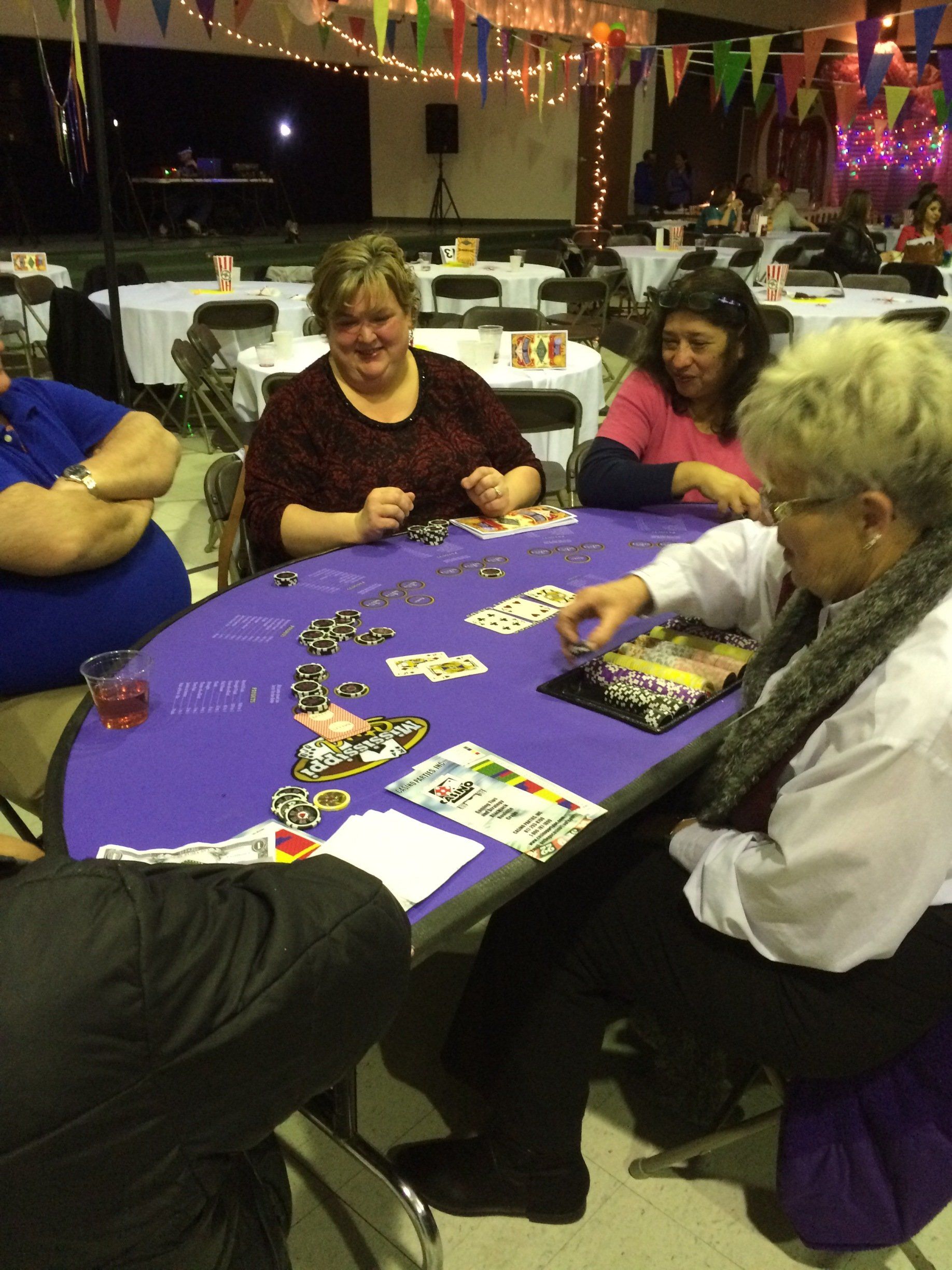 A group of people are sitting around a table playing cards