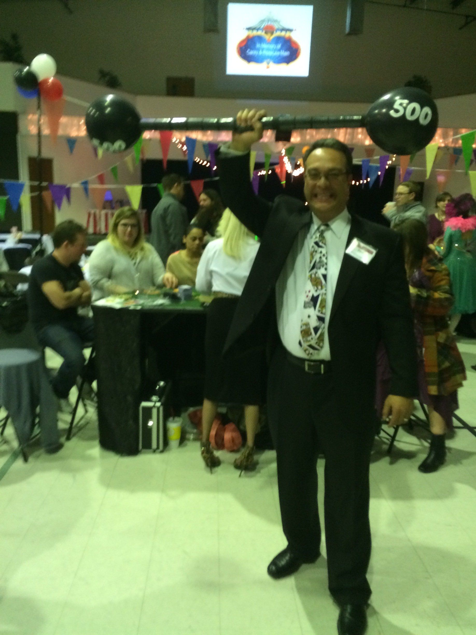 A man in a suit and tie holds up a balloon with the number 500 on it