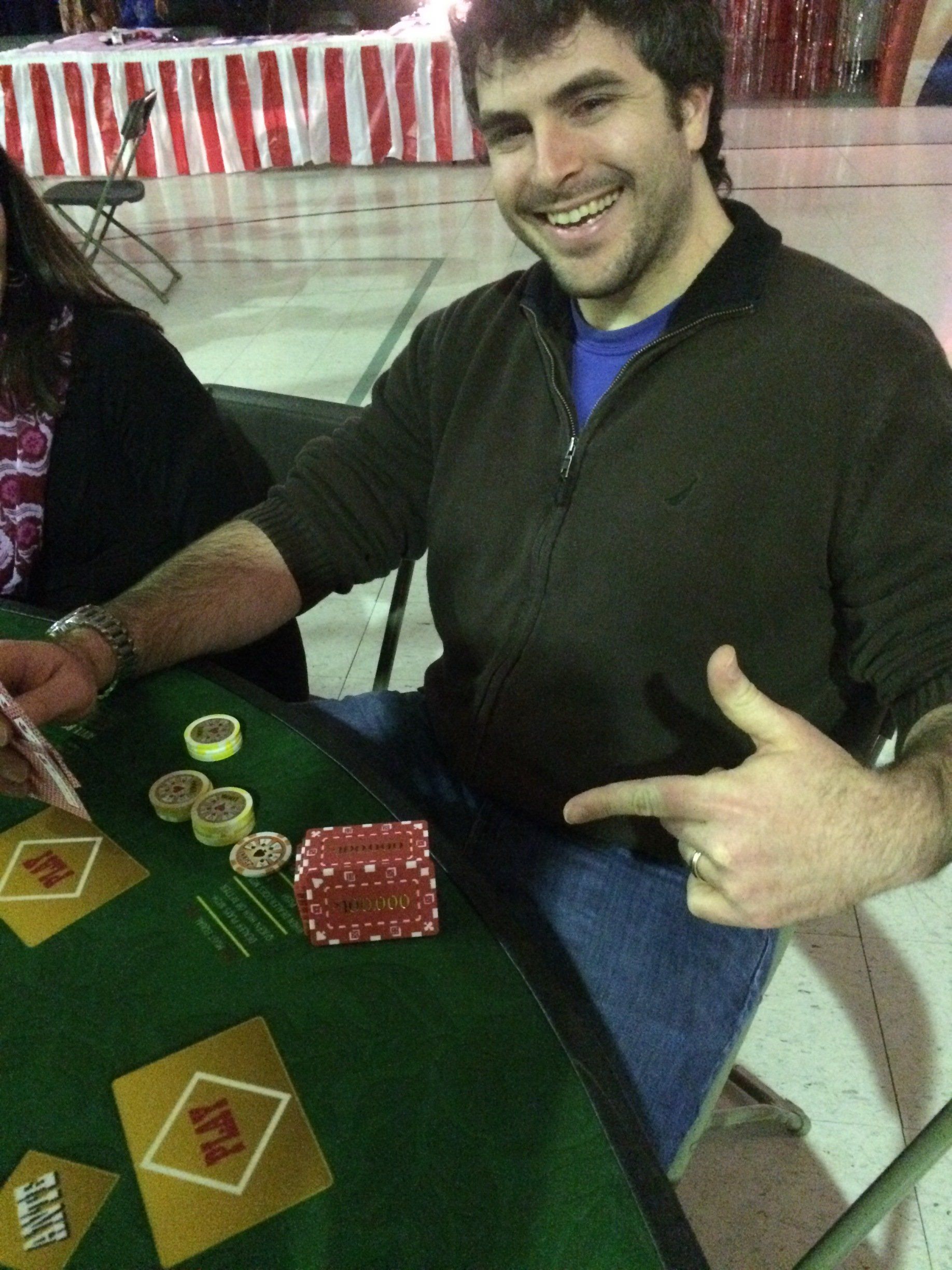 A man is sitting at a table playing poker and smiling