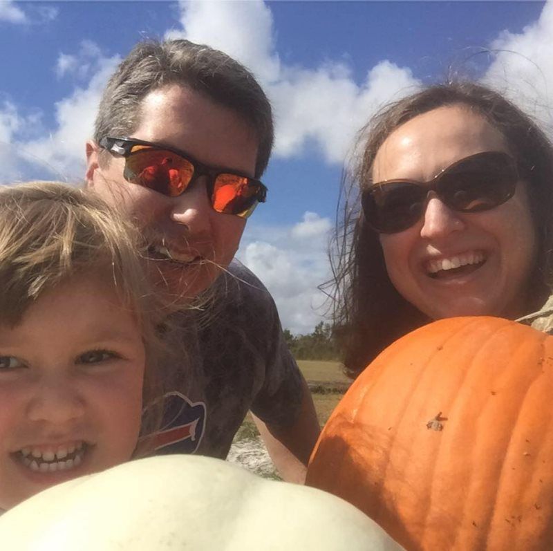 A family posing for a picture while holding pumpkins