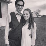 A man in a vest and bow tie is standing next to a woman in a white dress.