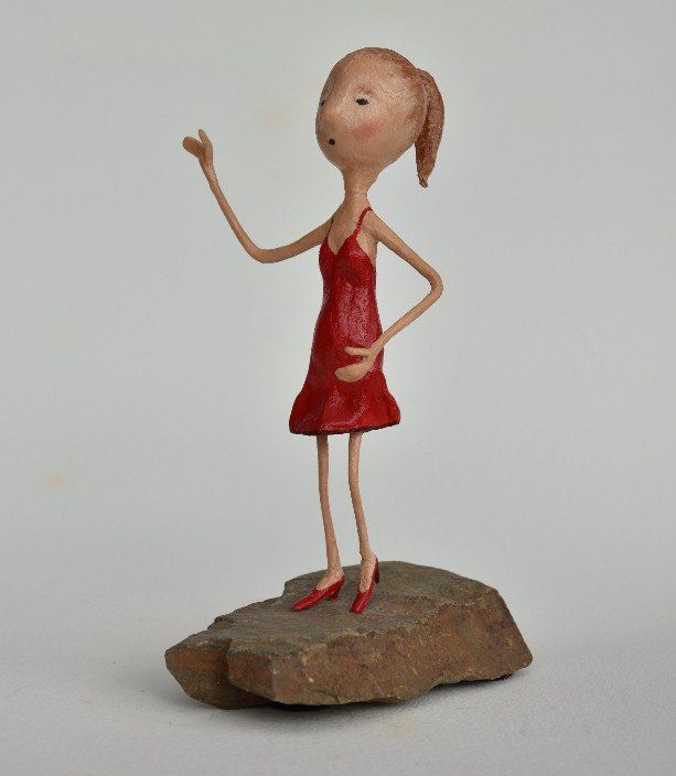 Een standbeeld van een vrouw in een rode jurk staand op een rots
