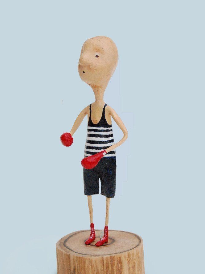 Een standbeeld van een man die op een stronk staat en een rood voorwerp vasthoudt