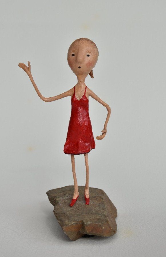 Een standbeeld van een vrouw in een rode jurk staand op een rots