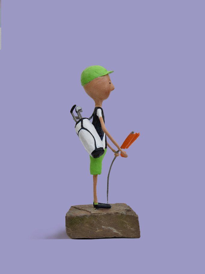 Een standbeeld van een man met een golfclub en een golftas