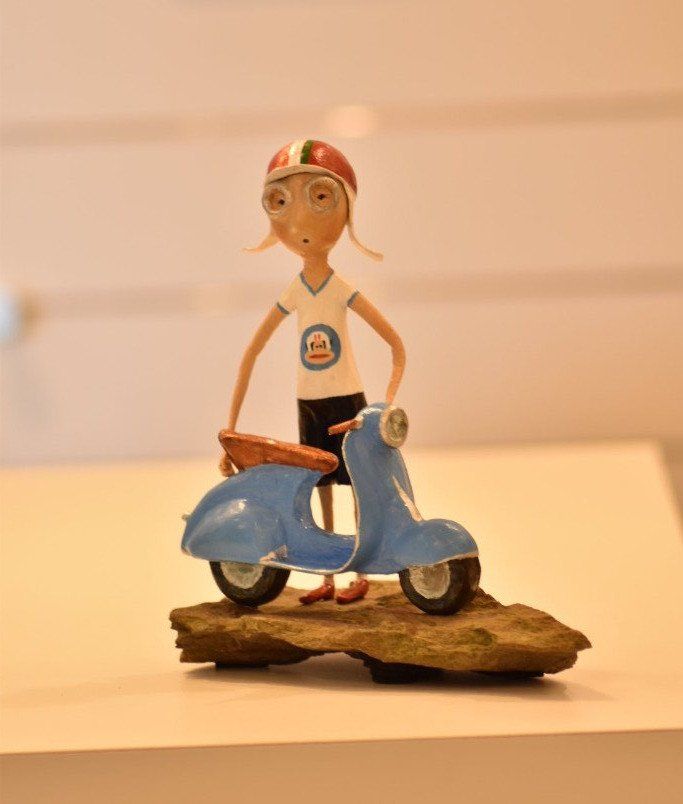 Een beeldje van een jongen die op een blauwe scooter rijdt