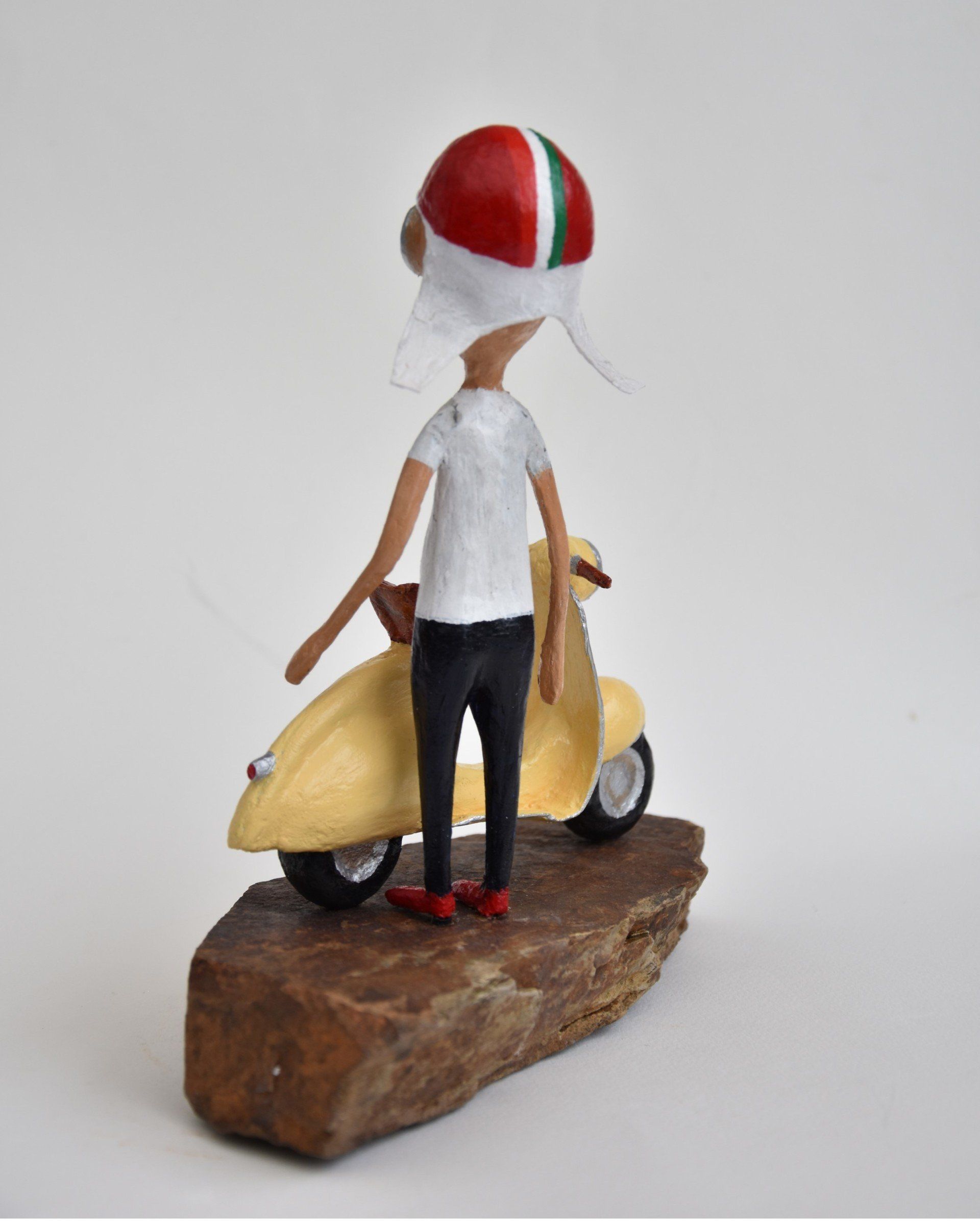 Een beeldje van een man op een scooter met een helm