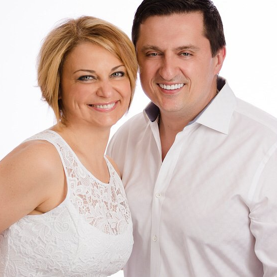 Smiling couple, woman in white dress, man in white shirt, studio portrait.