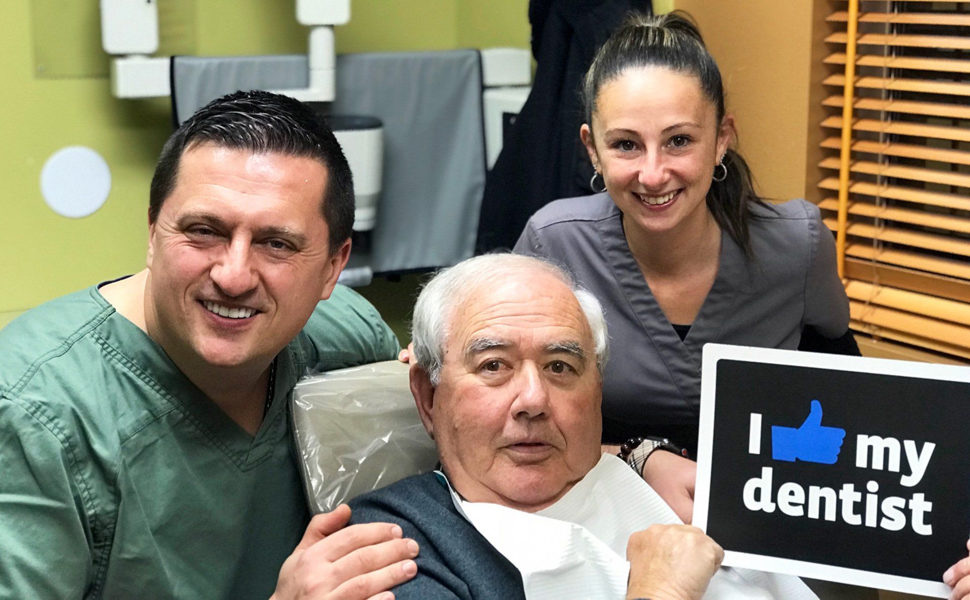 Dentist and assistant with smiling patient, holding 