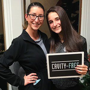 Two smiling women hold a sign: 