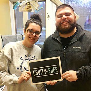 Two people smile, holding a 