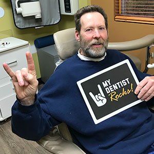 Man in dentist chair holding 