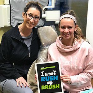 Two women smile, holding a sign that says 