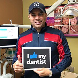 Man in a dental office, holding a sign saying 