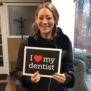 Woman smiles holding a sign that says 