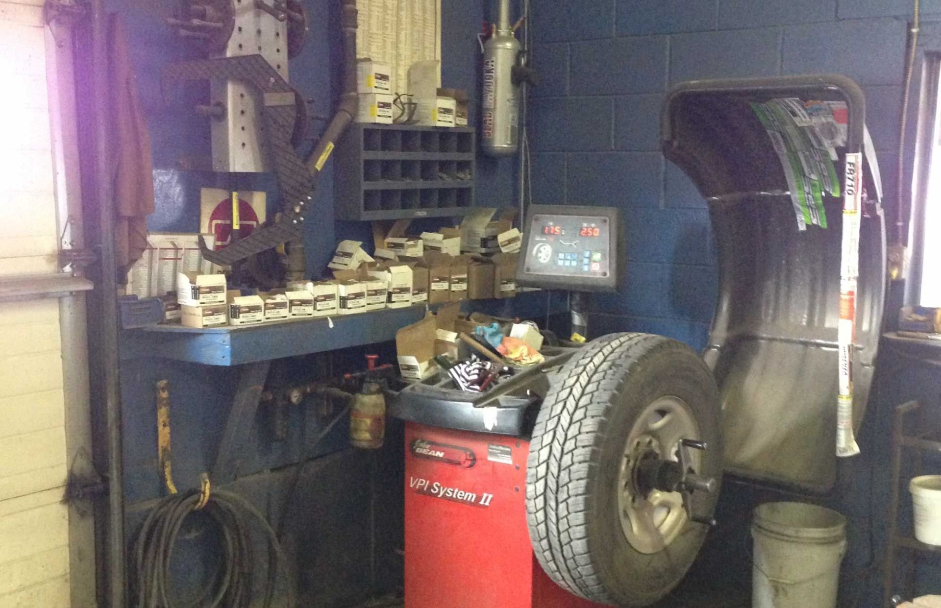 Atelier de réparation automobile avec un pneu de voiture, une armoire à outils rouge et un établi encombré d'outils