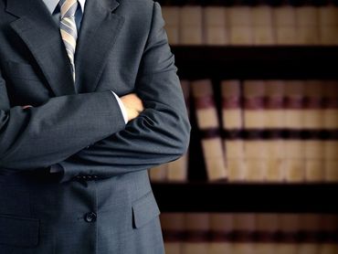 Hombre de traje con los brazos cruzados delante de una estantería.