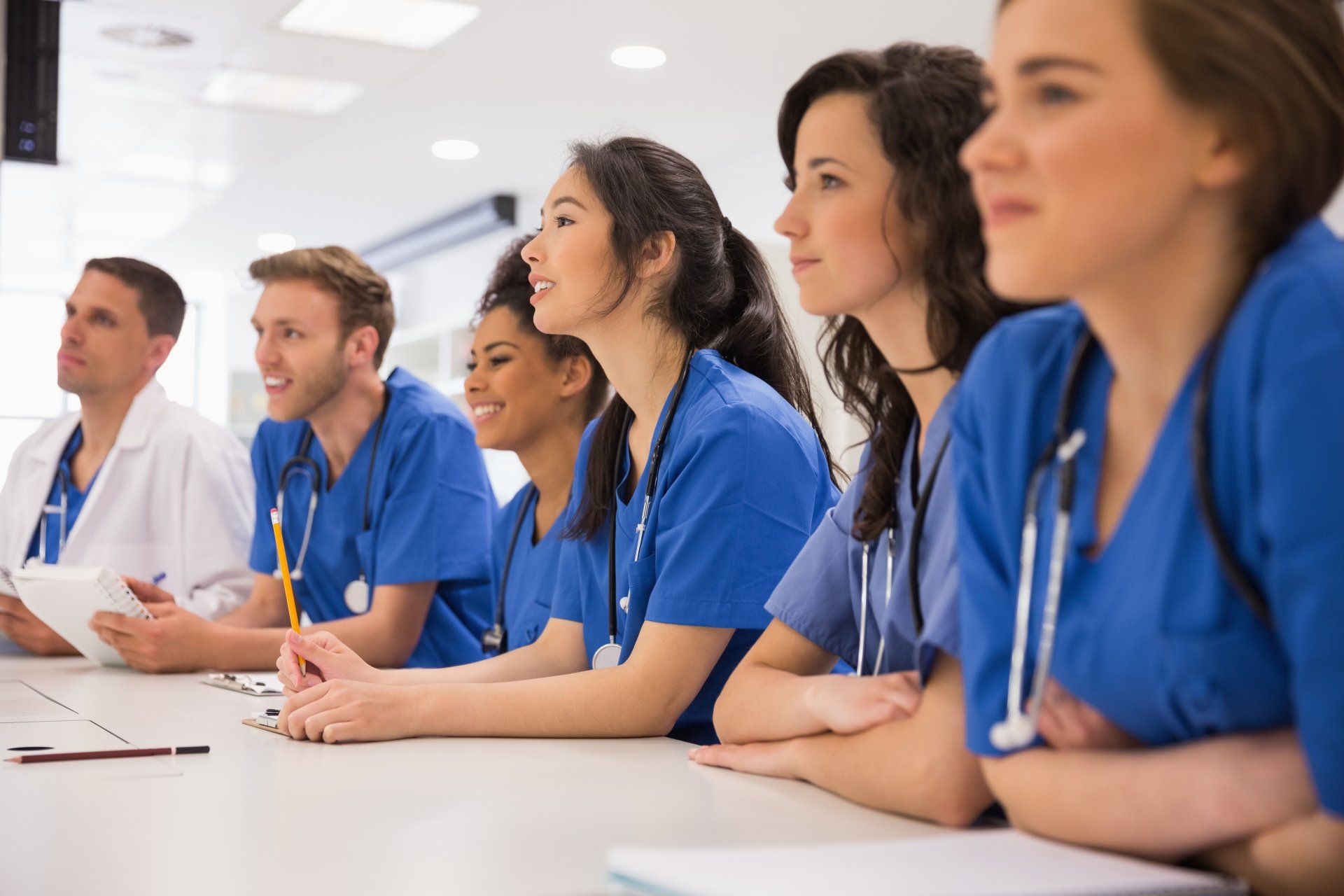A group of doctors and nurses are sitting at a table.