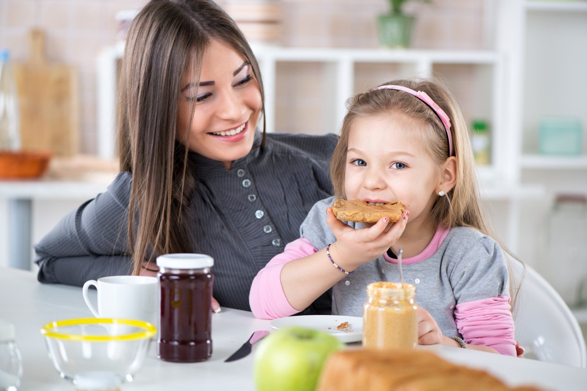 A woman and a little girl are sitting at a table eating food.