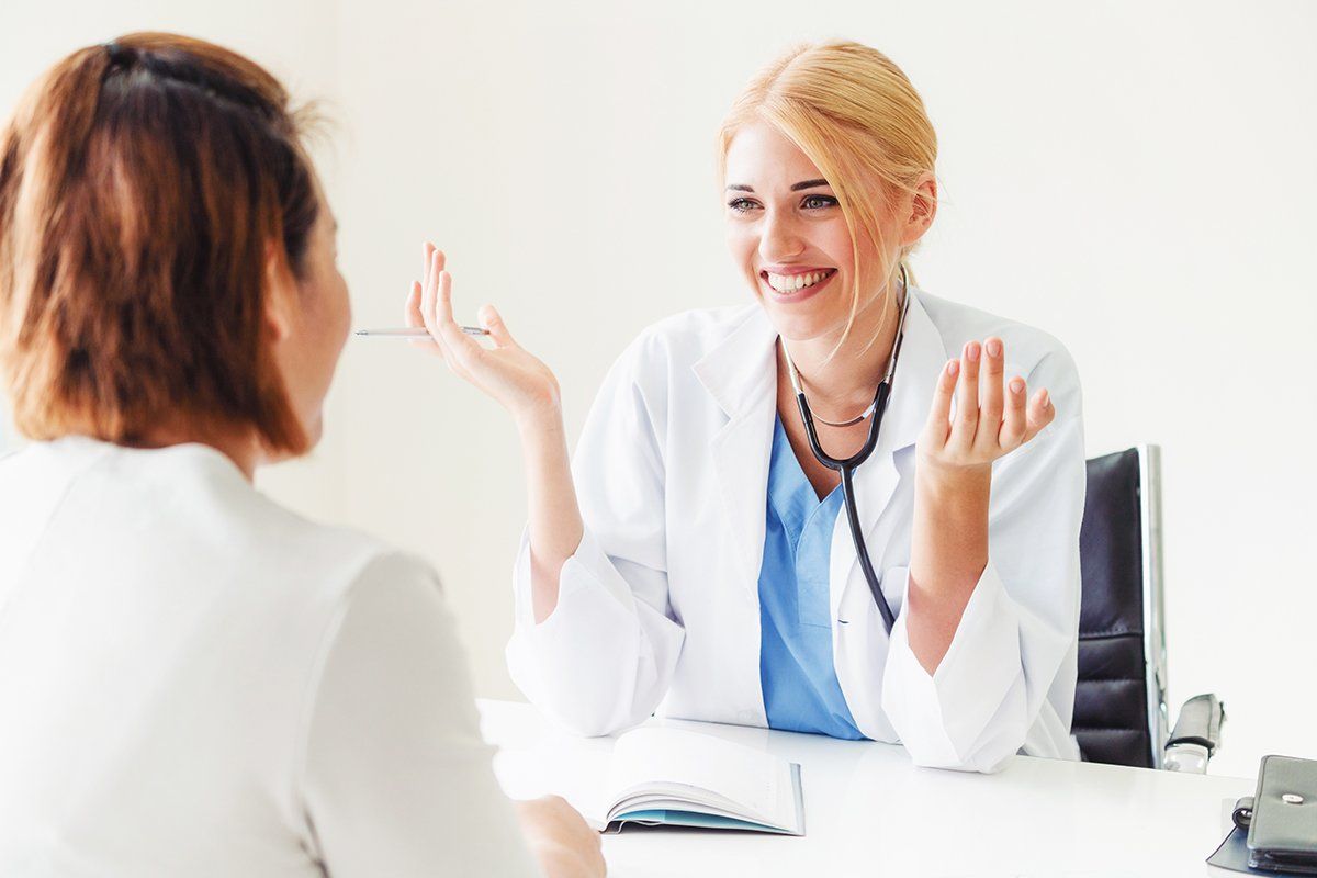 A doctor is sitting at a desk talking to a patient.