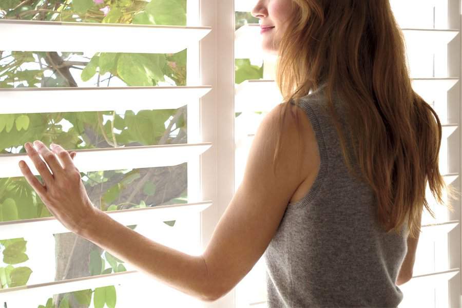 Woman moving her Hunter Douglas Palm Beach Shutters with her hands