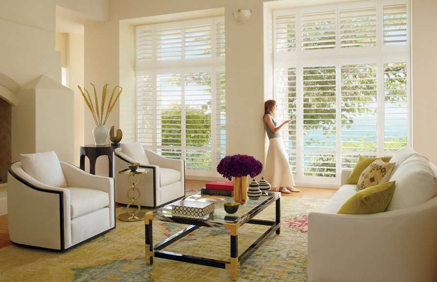 Woman in her living room controlling her motorized shutters with a remote