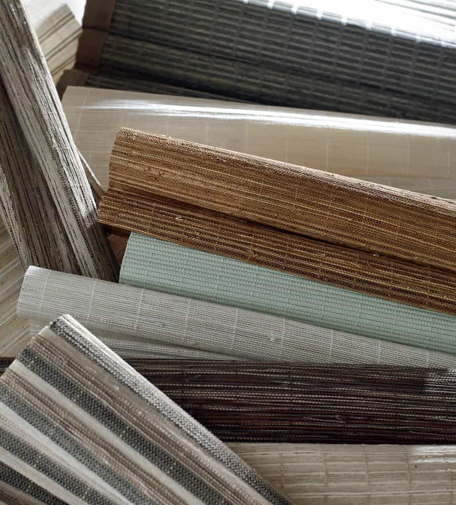 Assorted wood woven shades rolled up and in a pile