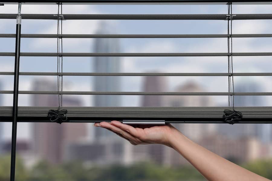 Woman lifting up Hunter Douglas Modern Precious Metals blinds set