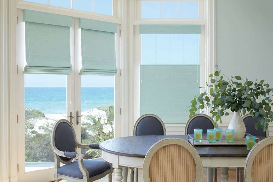 Wood woven shades covering windows in a dining room