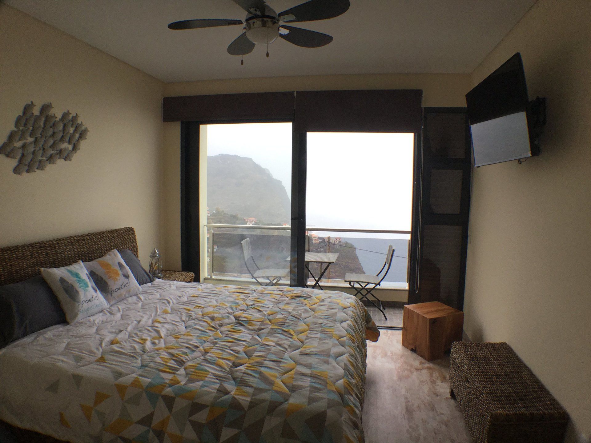 Schlafzimmer mit Bett, Balkon mit Meerblick, Fernseher und Dekofischen.