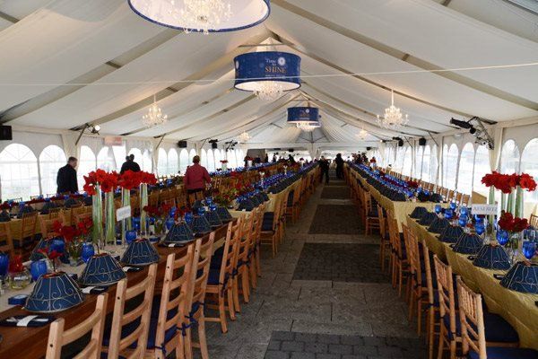 A long row of tables and chairs under a tent