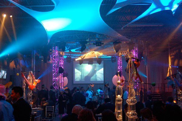 A crowd of people are gathered in a large room with a large screen on the wall
