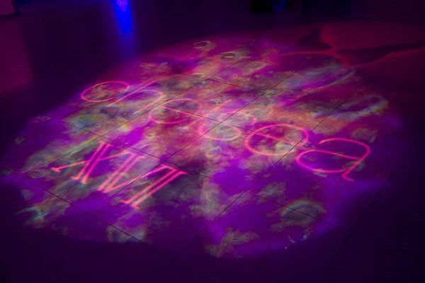 A purple light is projected on the floor in a dark room.