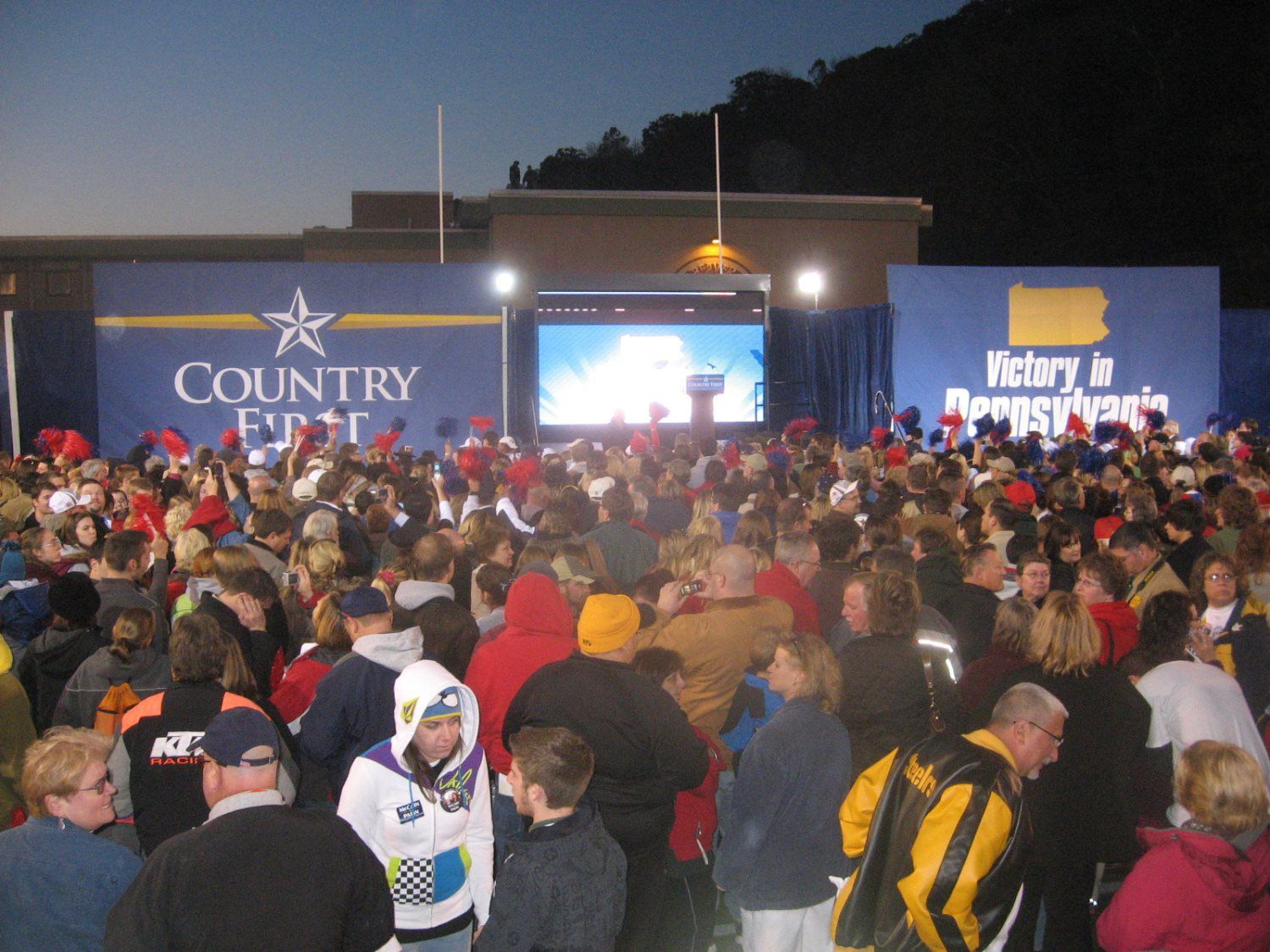 A crowd of people are gathered in front of a country fair sign