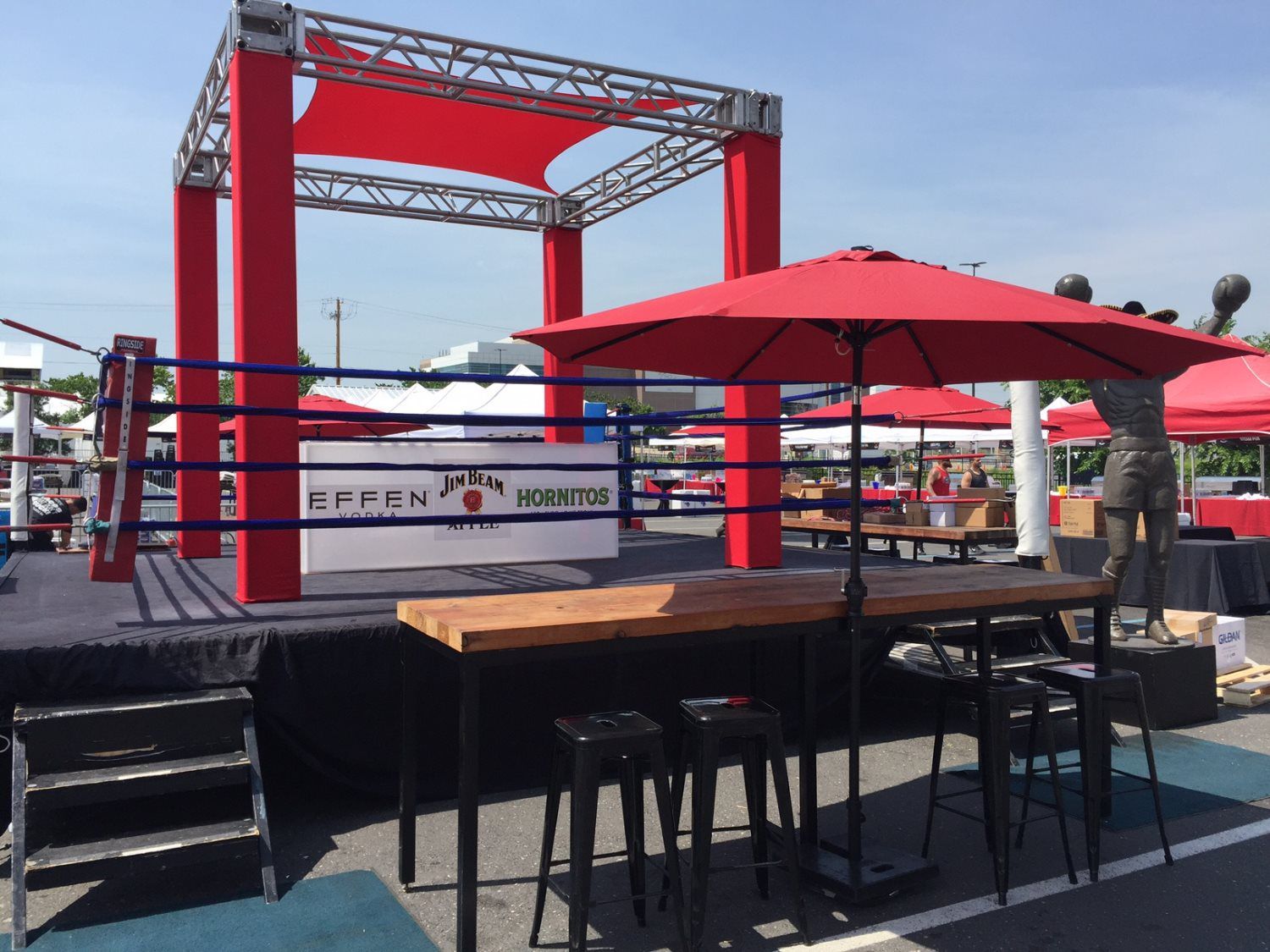 A boxing ring with tables and umbrellas in front of it