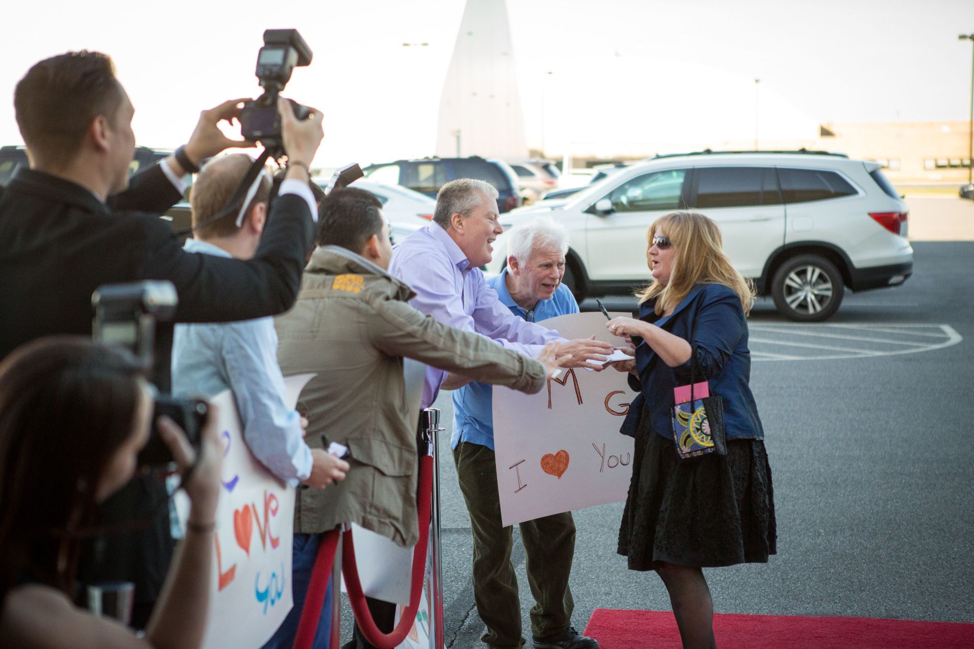 A group of people standing on a red carpet holding signs that say i love you.